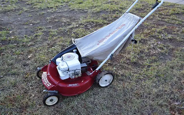 Walk-behind mower with a grass bag on a lawn